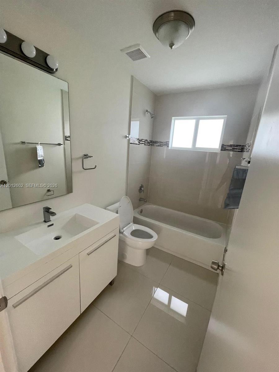 A bathroom features a white vanity, a toilet, and a bathtub with a shower head — 2121 NW 72nd St # 2121, Miami FL 33147, MIAMI, FL