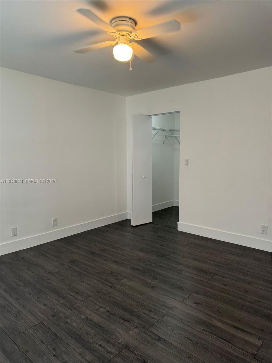 A bedroom features dark wood-look flooring, white walls, a ceiling fan, and an open closet — 1842 Madison St # 2, Hollywood FL 33020, HOLLYWOOD, FL