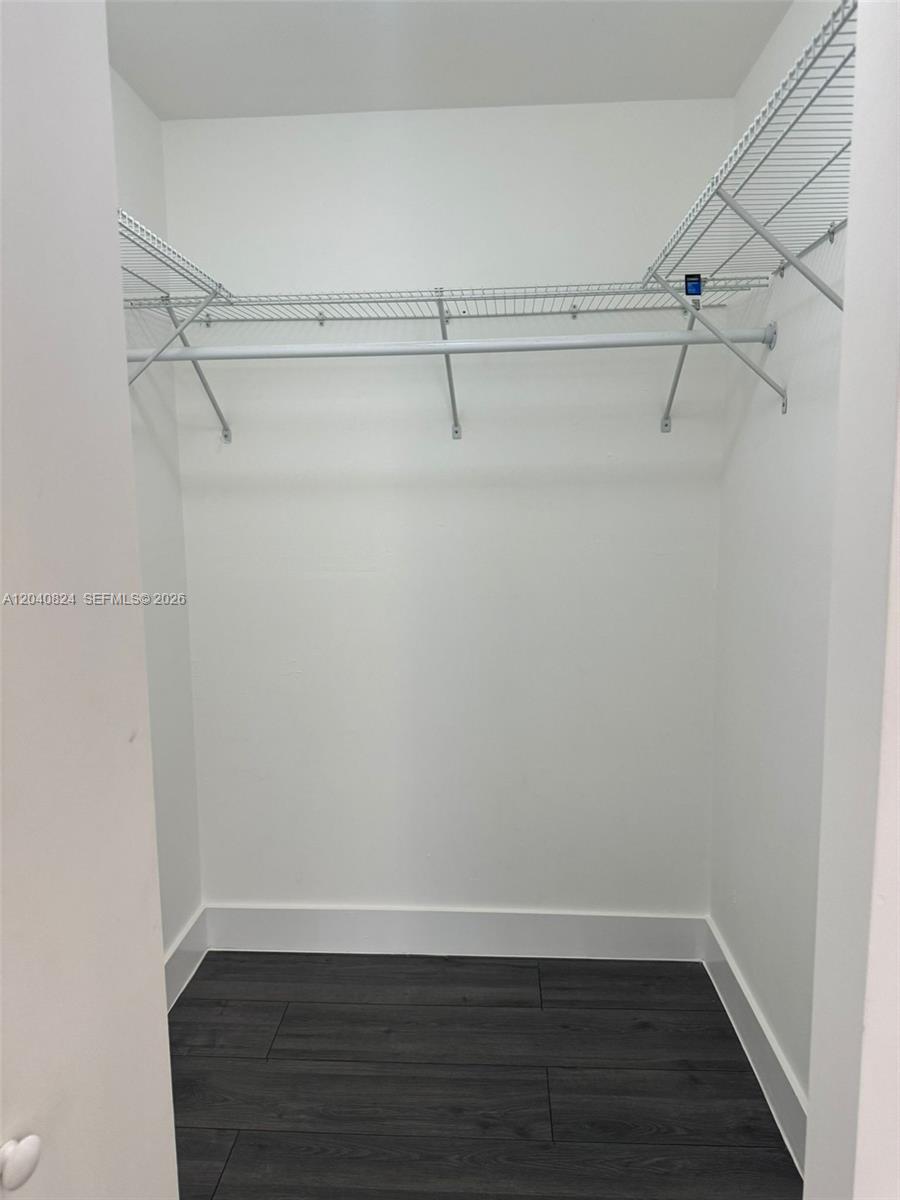 A walk-in closet features white walls, dark wood-look flooring, and wire shelving with a rod — 1842 Madison St # 2, Hollywood FL 33020, HOLLYWOOD, FL