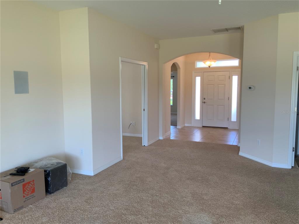 A carpeted living area leads to an arched entryway and a front door with sidelights — 27215 ROANOKE DRIVE, LEESBURG, FL