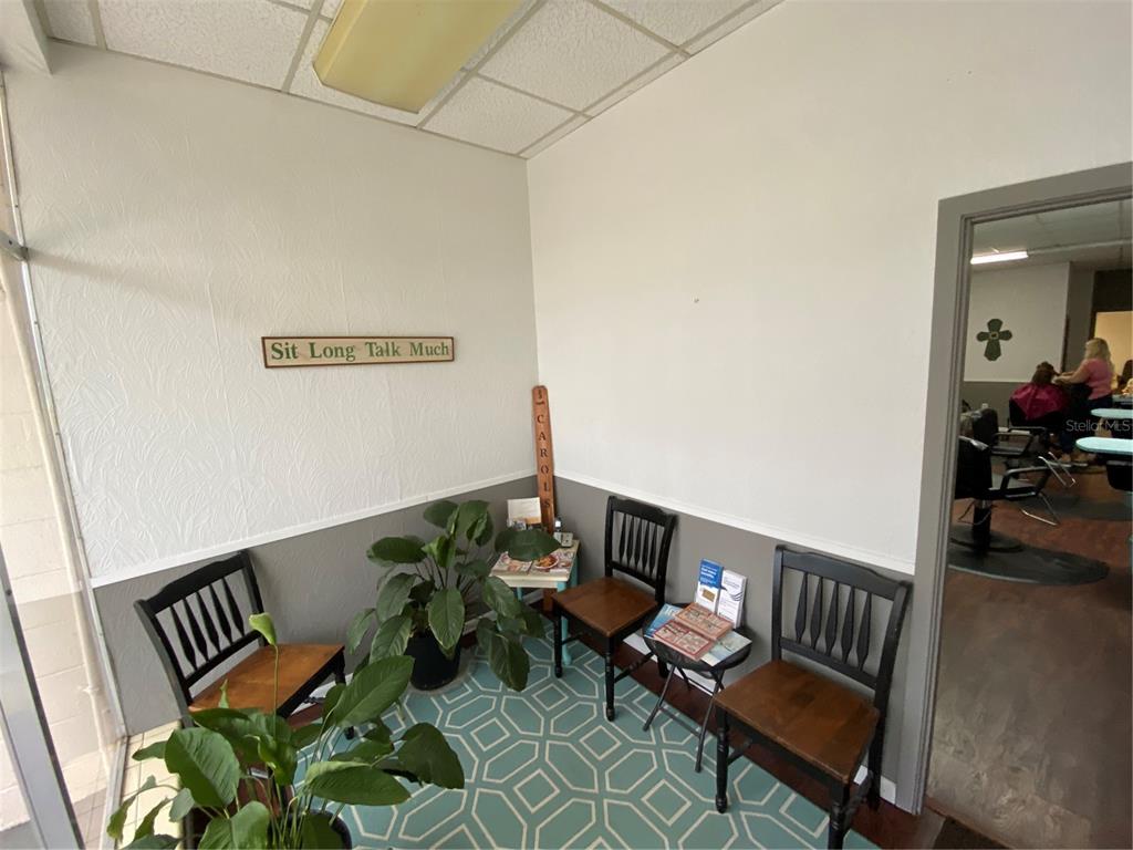 A waiting area with three wooden chairs, a potted plant, and wall decor — 207 N SCENIC HIGHWAY UNIT 207 & 211, FROSTPROOF, FL