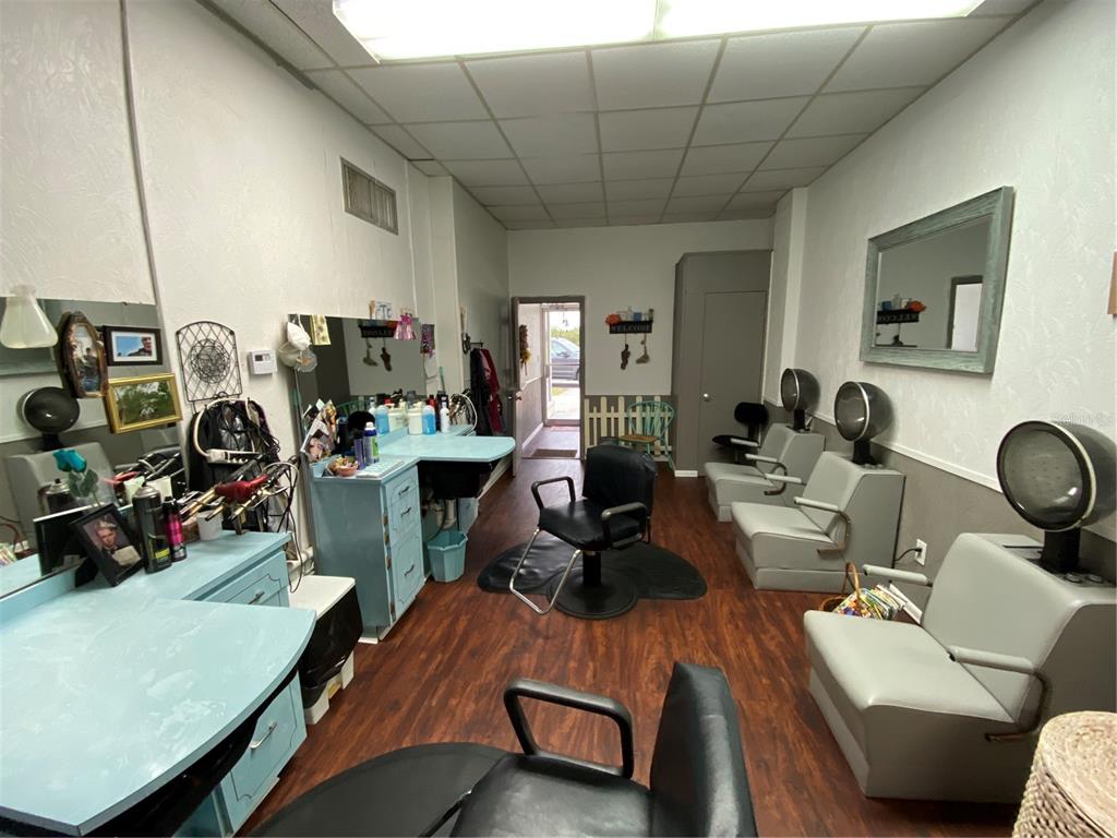 A hair salon features multiple styling stations, hooded dryers, light blue cabinetry, and wood-look flooring — 207 N SCENIC HIGHWAY UNIT 207 & 211, FROSTPROOF, FL