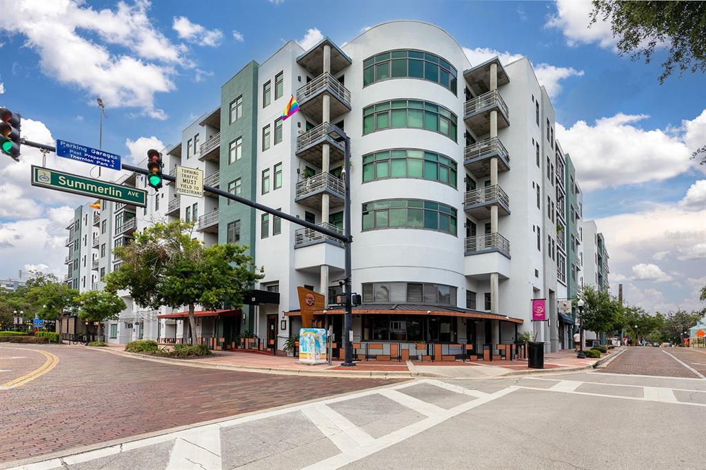 A multi-story apartment building with a curved glass facade stands at a brick intersection — 10 N SUMMERLIN AVENUE UNIT 14, ORLANDO, FL