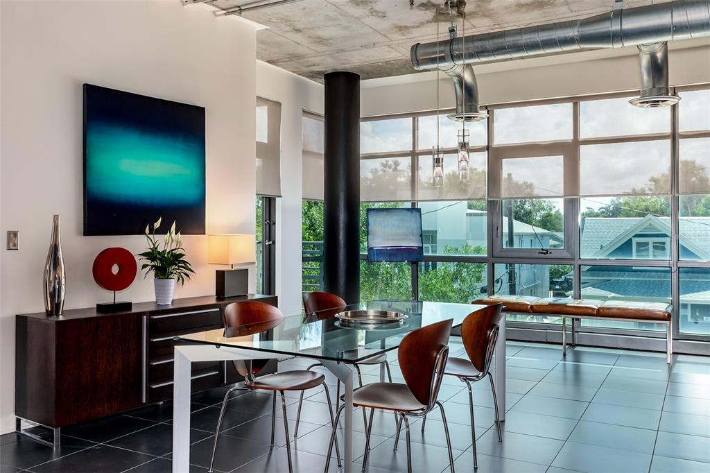 A modern dining room features a glass table, wood chairs, and exposed industrial ceiling ducts — 10 N SUMMERLIN AVENUE UNIT 14, ORLANDO, FL