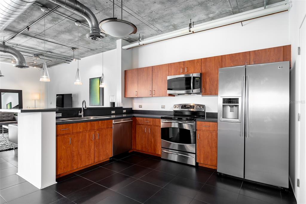 A modern kitchen features wood cabinets, stainless steel appliances, and a concrete ceiling — 10 N SUMMERLIN AVENUE UNIT 14, ORLANDO, FL