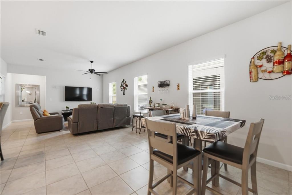 An open-concept living and dining area features tile flooring, a gray sofa, and a dining set — 3979 CAPITAL REEF WAY, APOPKA, FL