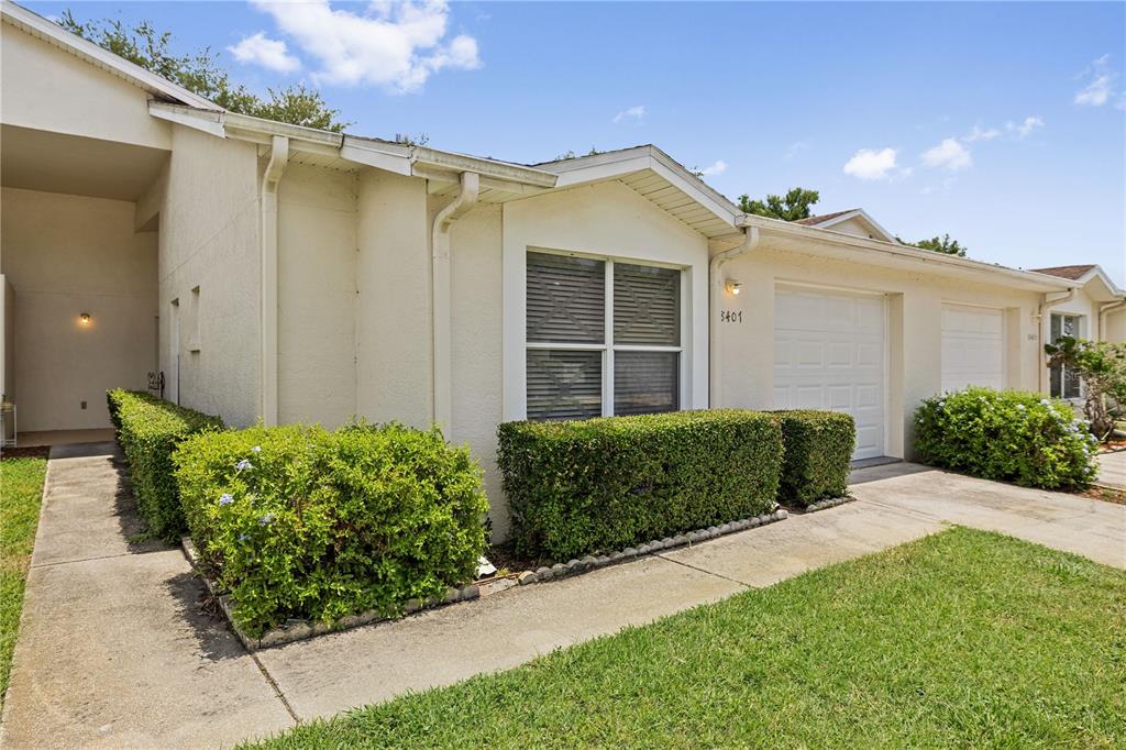 A single-story residential building with a white stucco exterior, a garage, and manicured hedges — 8407 TERRACE MEADOWS COURT UNIT N/A, TAMPA, FL