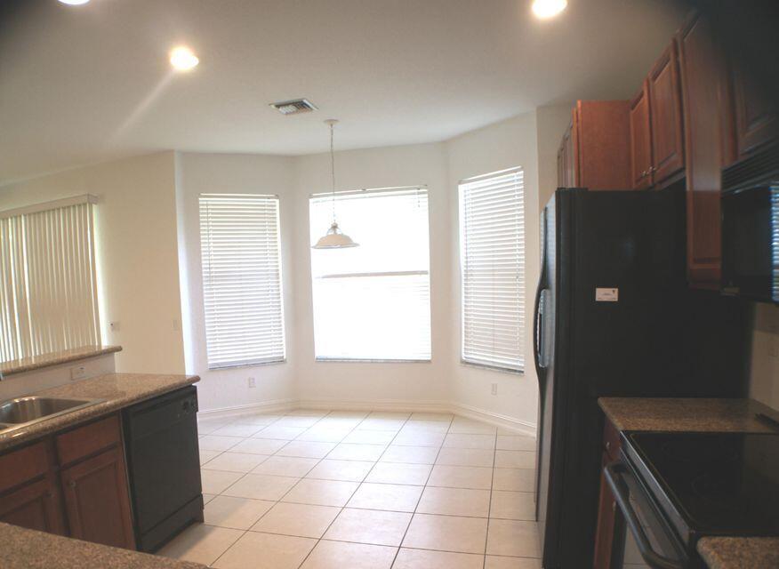 A kitchen with tile flooring, granite countertops, dark wood cabinets, and a breakfast nook area — 8887 Chestnut Ridge Way, Boynton Beach FL 33473, BOYNTON BEACH, FL