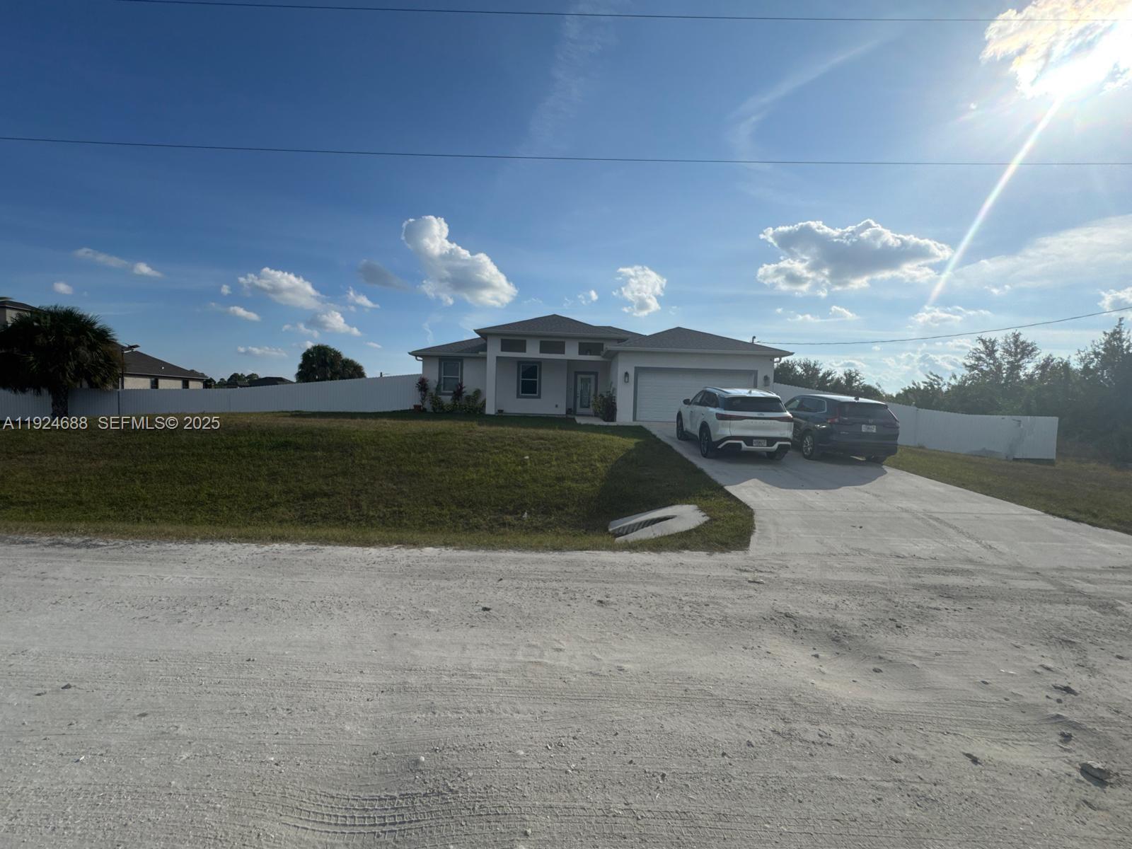 A single-story house with a white exterior, a two-car garage, and a concrete driveway — 7799 16th Place,, La Belle FL 33935, LA BELLE, FL