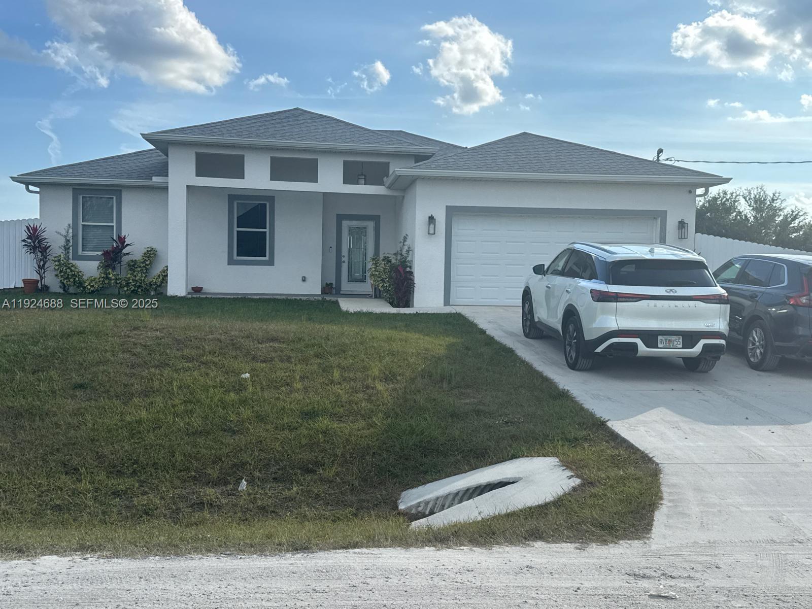 A single-story white house with a two-car garage and a driveway sits on a lawn — 7799 16th Place,, La Belle FL 33935, LA BELLE, FL
