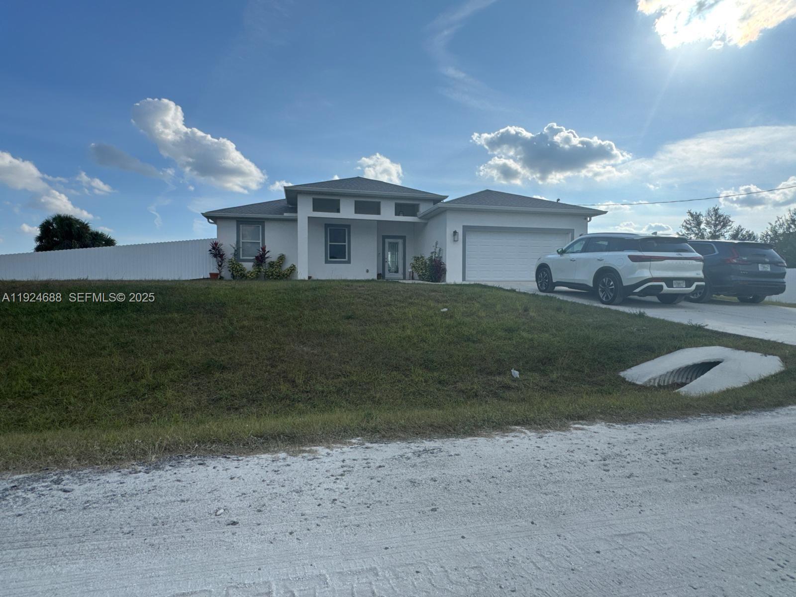 A single-story house with a white exterior, a two-car garage, and a sloped grassy lawn — 7799 16th Place,, La Belle FL 33935, LA BELLE, FL