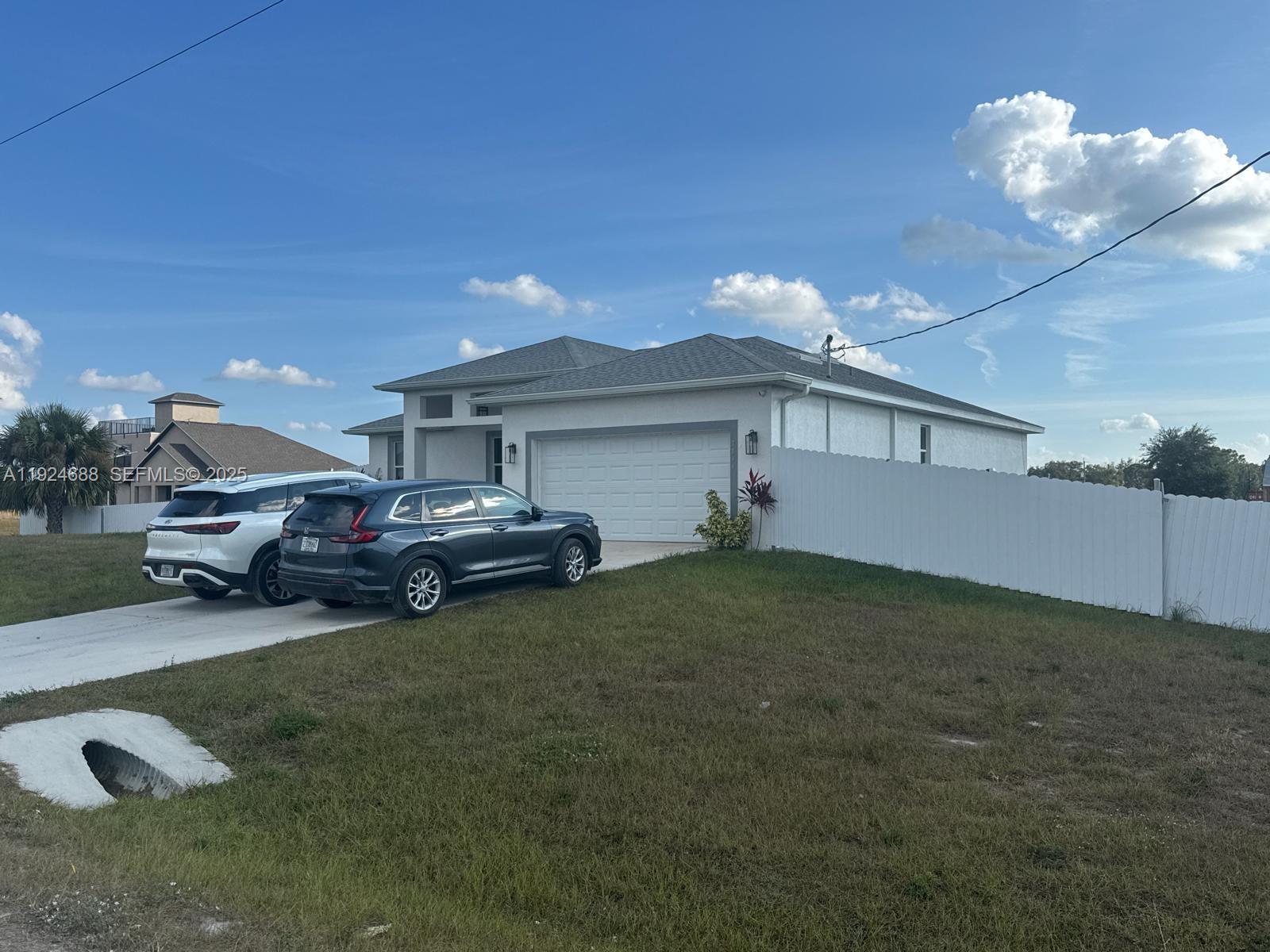 A single-story house with a white garage and two cars parked in the driveway — 7799 16th Place,, La Belle FL 33935, LA BELLE, FL