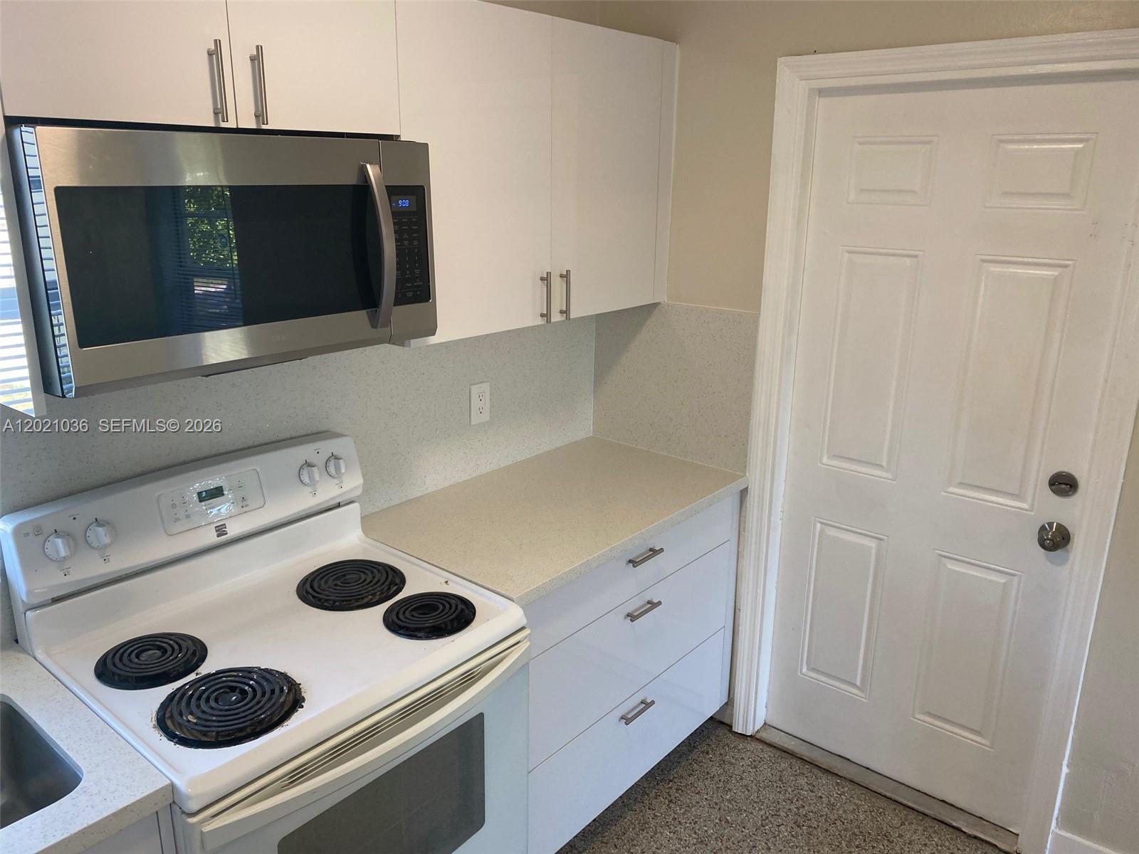 A kitchen features white cabinets, a stainless steel microwave, a white stove, and countertops — 2325 N 25th Ave # 2325, Hollywood FL 33020, HOLLYWOOD, FL