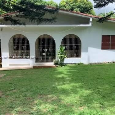 A white single-story house features three arched entryways with metal security grilles and a lawn — 00 Stony Hill, Kingston, NA, NA