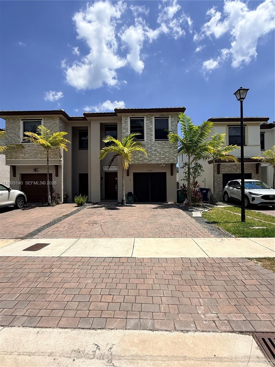 A two-story townhouse with a stone facade, a brick driveway, and palm trees — 25441 SW 109th Ave, Homestead FL 33032, HOMESTEAD, FL