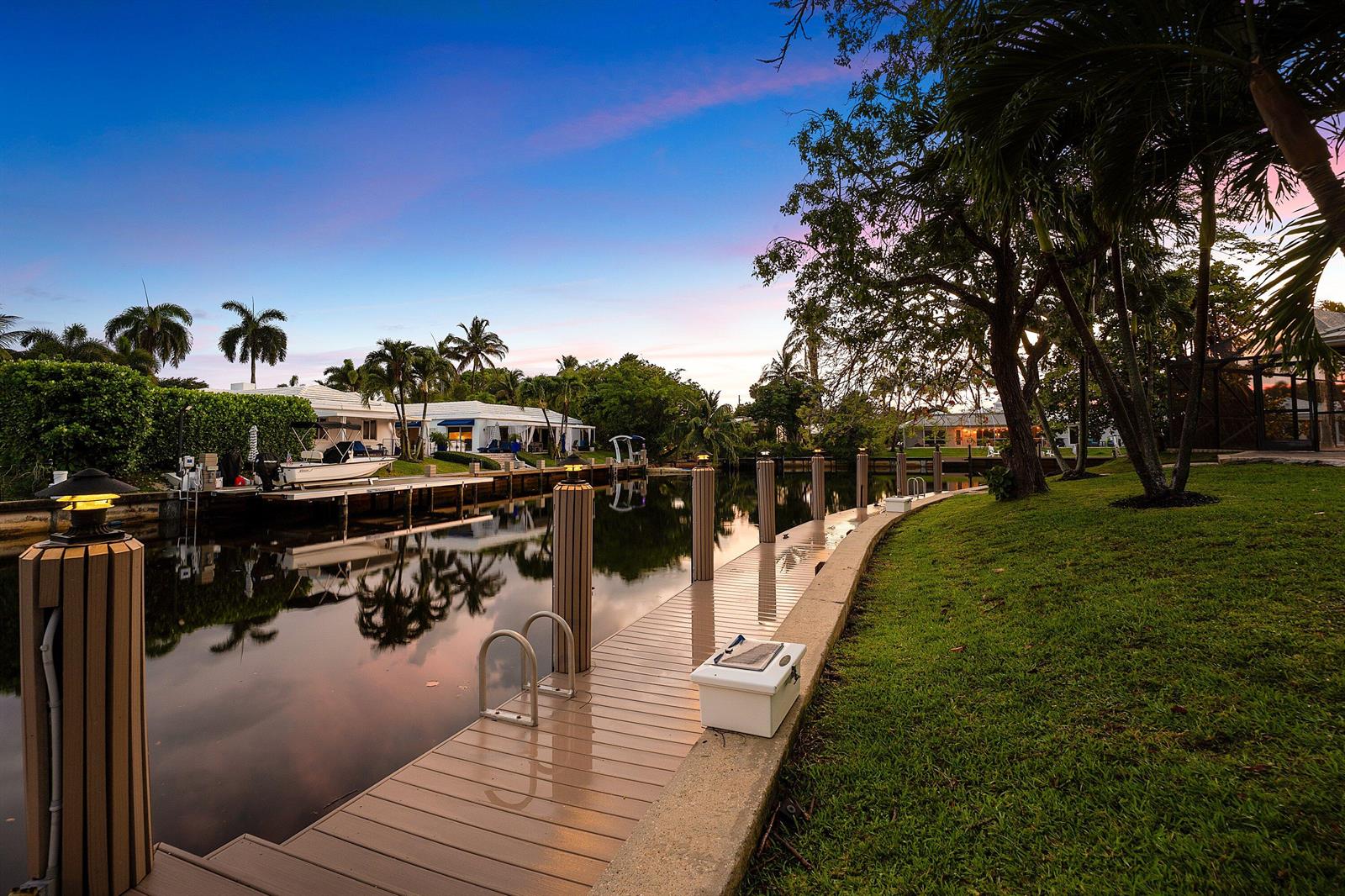 A wooden dock with lights and a boat lift sits along a canal at sunset — 770 Peachtree Lane, Boca Raton FL 33486, BOCA RATON, FL
