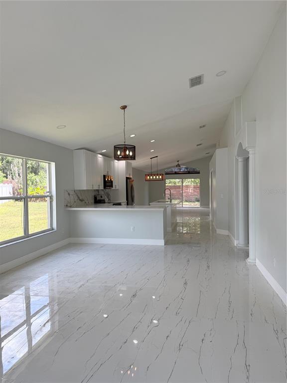 A bright, open-concept kitchen and living area features white marble-look tile floors and cabinetry — 9067 HASTINGS BEACH BOULEVARD, ORLANDO, FL