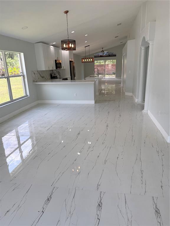 A kitchen and living area featuring white marble-look tile flooring and white cabinetry — 9067 HASTINGS BEACH BOULEVARD, ORLANDO, FL