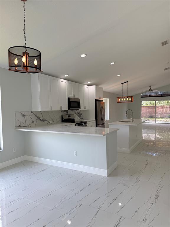 A modern kitchen features white cabinets, marble-patterned countertops, and matching tile flooring — 9067 HASTINGS BEACH BOULEVARD, ORLANDO, FL