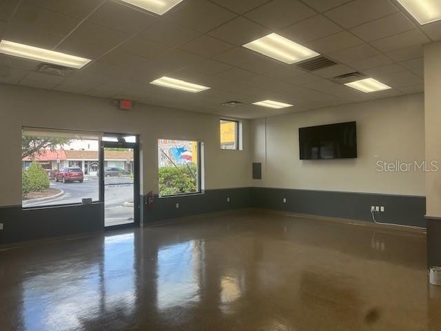 An empty commercial space features a polished floor, drop ceiling, and a wall-mounted television — 110 S COLLINS STREET, PLANT CITY, FL
