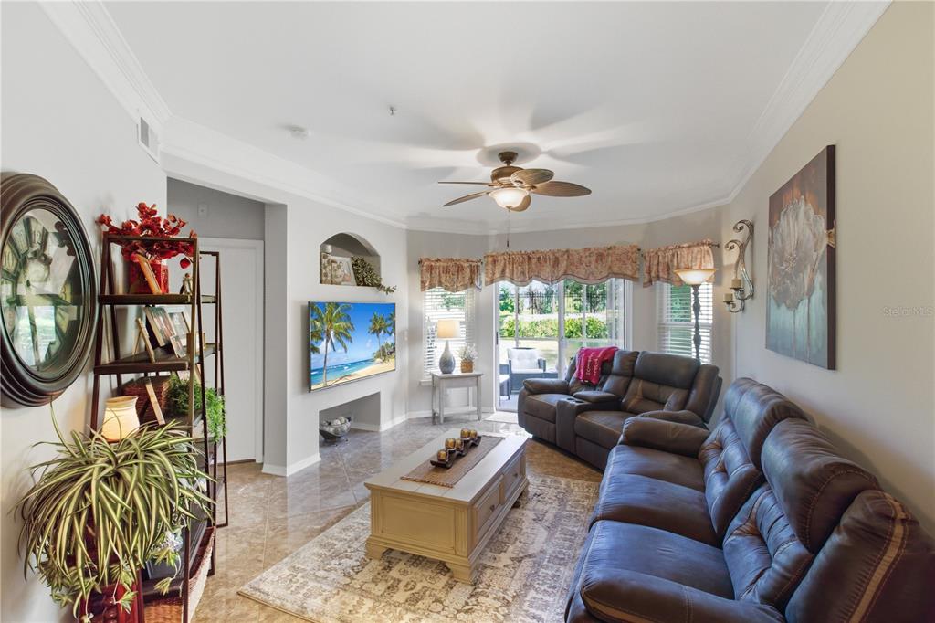 A living room features a leather sofa, a coffee table, a television, and a ceiling fan — 5122 NORTHRIDGE ROAD UNIT 107, SARASOTA, FL