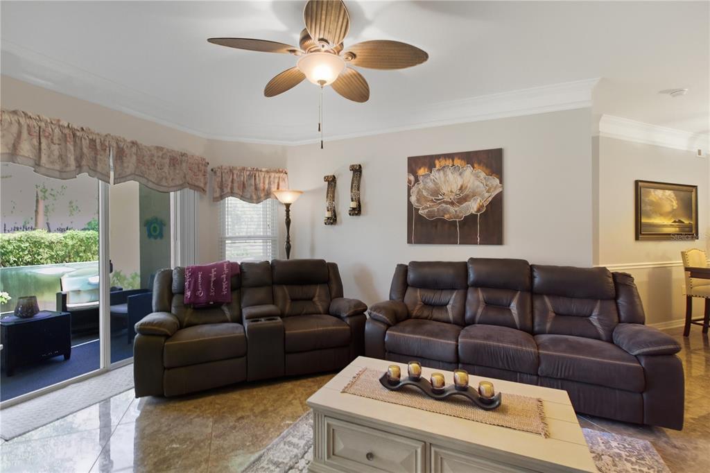 A living room features two brown leather sofas, a coffee table, and a ceiling fan — 5122 NORTHRIDGE ROAD UNIT 107, SARASOTA, FL