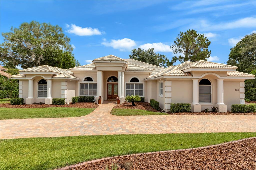 A single-story beige house with a tiled roof, columns, and a paved driveway — 236 EAGLE ESTATES DRIVE, DEBARY, FL