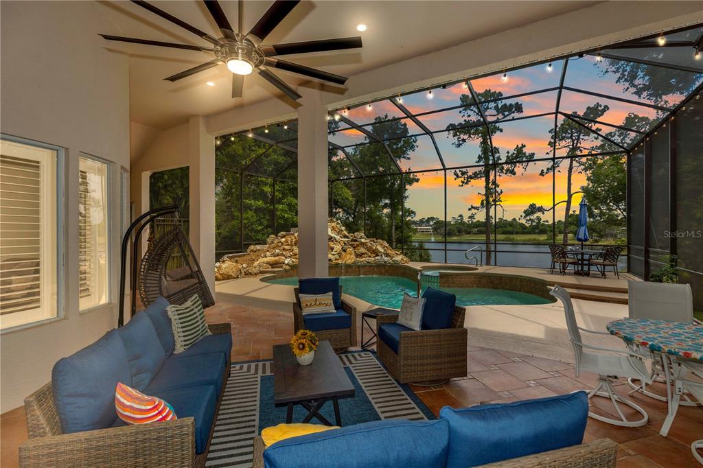 A covered patio features a pool, a rock waterfall, and a view of a lake — 236 EAGLE ESTATES DRIVE, DEBARY, FL
