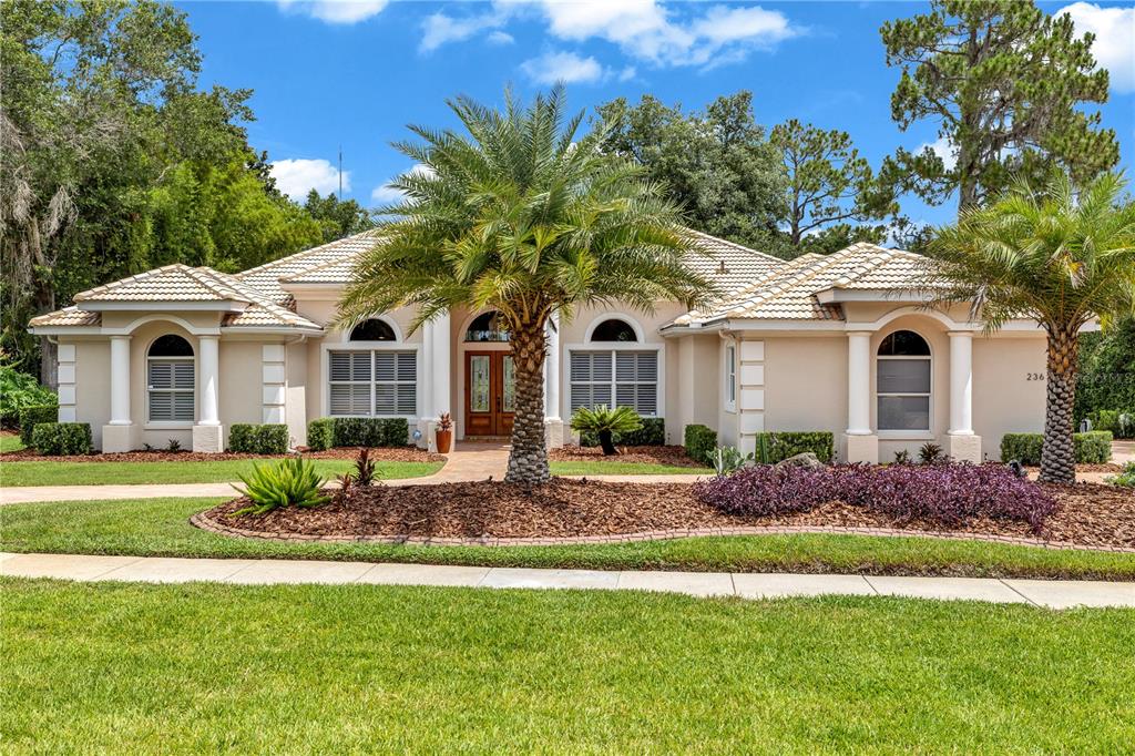 A single-story house with a tiled roof, arched windows, and two prominent palm trees — 236 EAGLE ESTATES DRIVE, DEBARY, FL