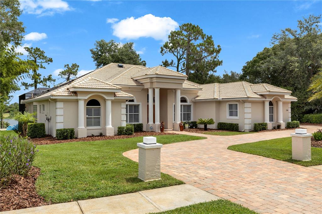 A single-story house with a beige stucco exterior, tiled roof, and a paved driveway — 236 EAGLE ESTATES DRIVE, DEBARY, FL