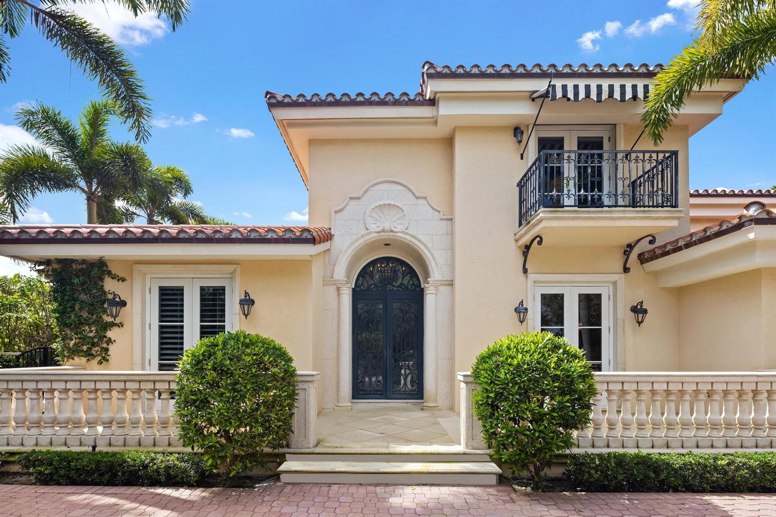 A Mediterranean-style house features a central arched doorway, a balcony, and a stone balustrade — 1460 N Ocean Boulevard, Palm Beach FL 33480, PALM BEACH, FL