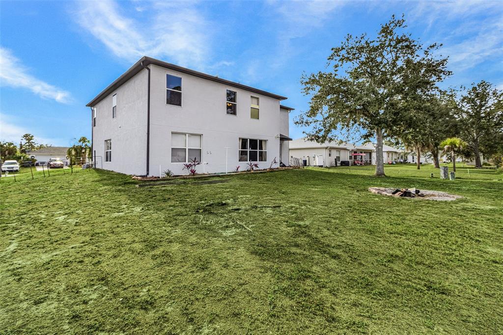 The exterior of a two-story white house features a large backyard with a fire pit — 2496 WURTSMITH, NORTH PORT, FL