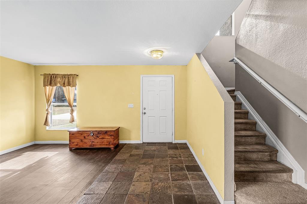 An entryway features yellow walls, tile flooring, a wooden chest, and stairs with carpet — 2496 WURTSMITH, NORTH PORT, FL
