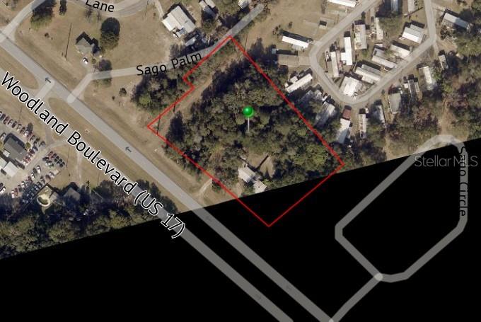 This is an aerial map showing a property outlined in red near a highway — 2401 N WOODLAND BOULEVARD, DELAND, FL