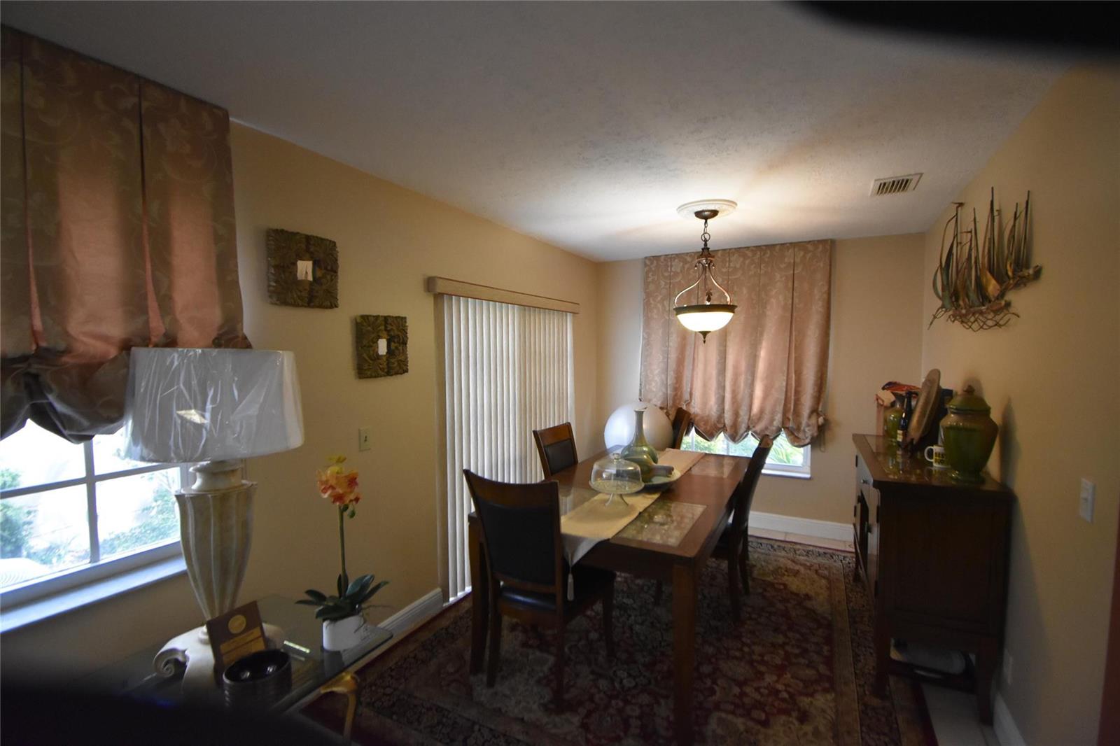 A dining room features a wooden table, chairs, a chandelier, and a patterned area rug — 6572 Bayfront Drive, Margate FL 33063, MARGATE, FL