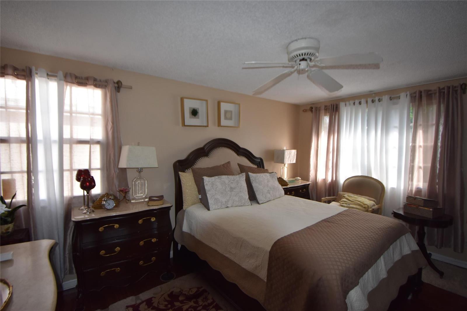 A bedroom features a dark wood bed frame, a matching dresser, and a ceiling fan — 6572 Bayfront Drive, Margate FL 33063, MARGATE, FL