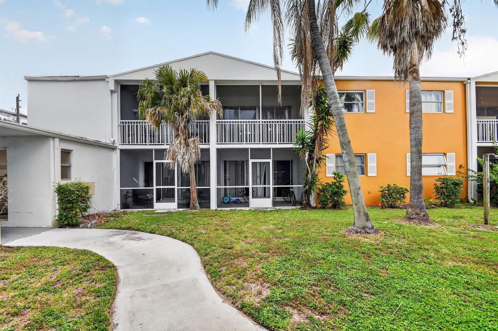 A two-story apartment building features screened-in balconies and patios facing a grassy lawn — 1505 Crescent Circle # B24, Lake Park FL 33403, LAKE PARK, FL