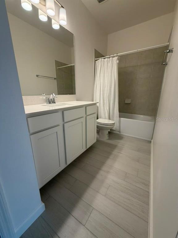 A bathroom features a white vanity, a mirror, a toilet, and a shower-tub combination — 5197 PRAIRIE PRESERVE RUN, ST CLOUD, FL