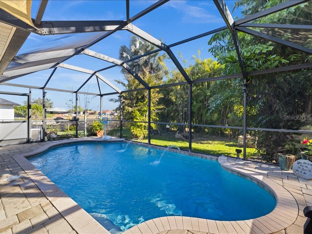 A screened-in swimming pool with a paver deck and a view of the backyard — 1209 NW 25TH PLACE, CAPE CORAL, FL