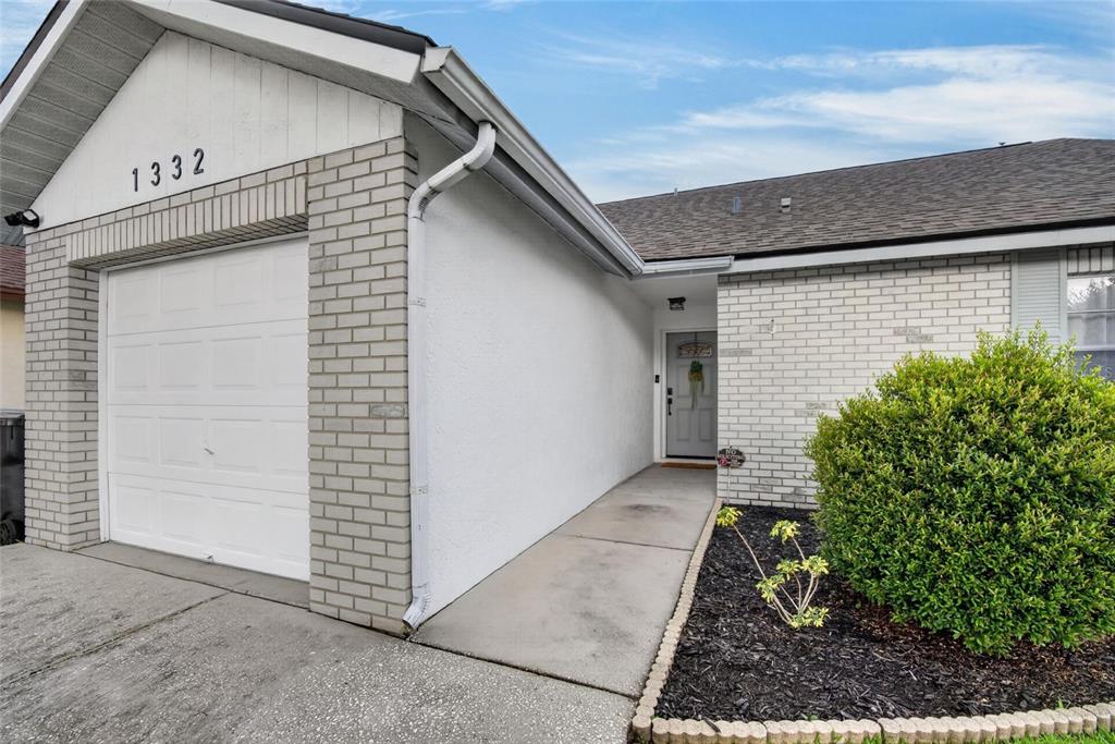 The exterior of a house features a white garage, a brick facade, and a front entryway — 1332 COOLRIDGE DRIVE, BRANDON, FL