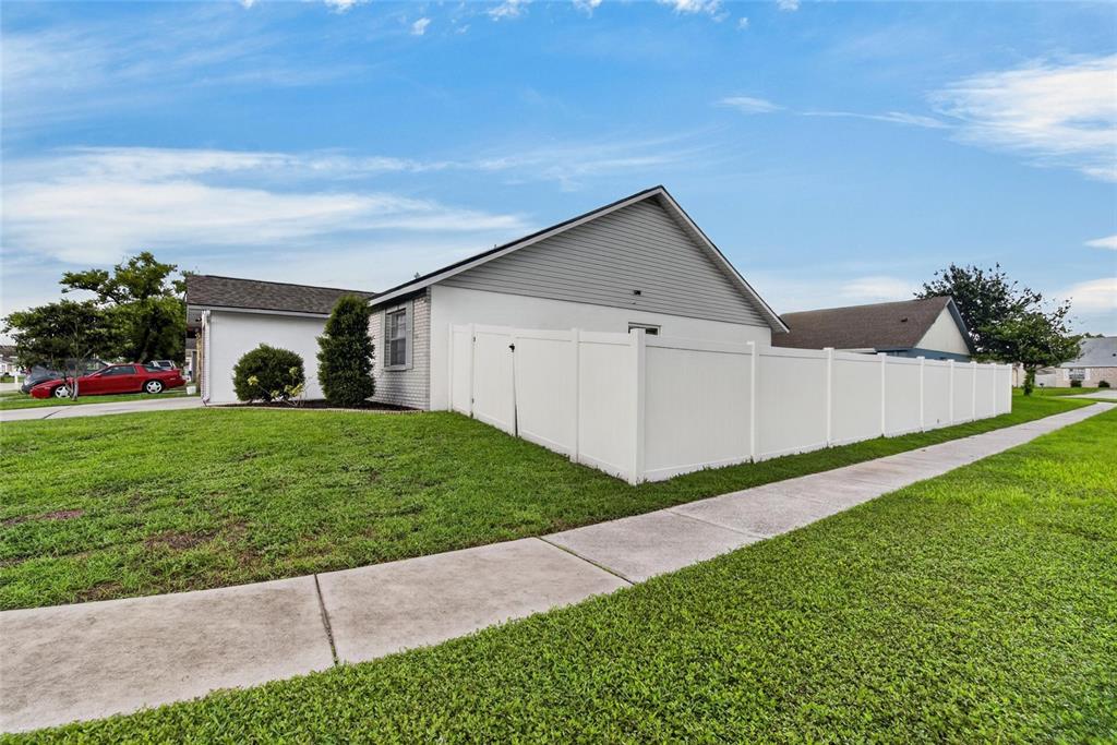 A white vinyl fence encloses the side yard of a single-story house with gray siding — 1332 COOLRIDGE DRIVE, BRANDON, FL