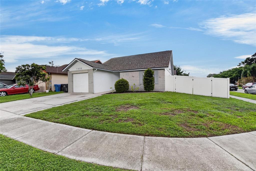A single-story house with a white garage, brick facade, and a white vinyl privacy fence — 1332 COOLRIDGE DRIVE, BRANDON, FL