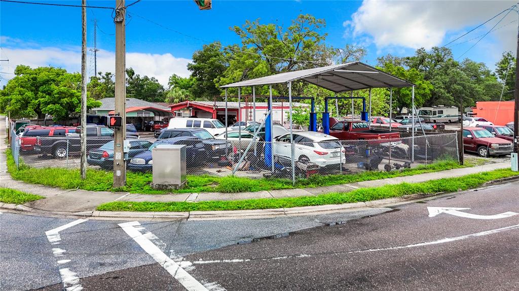 An outdoor auto repair lot features a metal canopy over several parked vehicles — 1412 E LAKE AVENUE, TAMPA, FL
