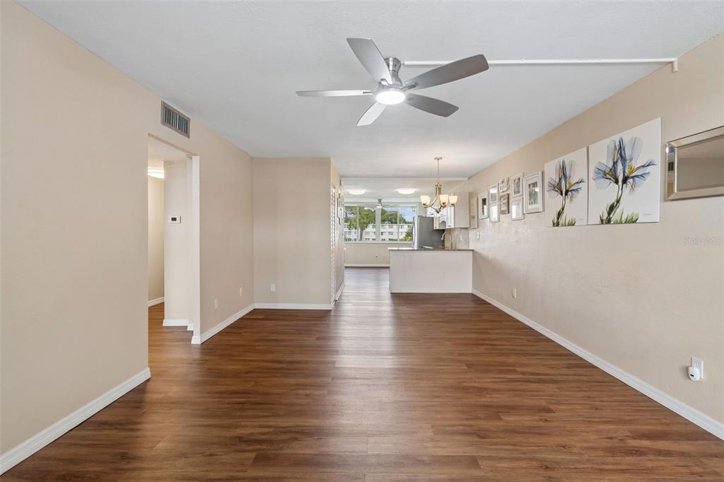 An open-concept living area features wood-look flooring, beige walls, and a ceiling fan — 4715 BAY STREET NE UNIT 223, ST PETERSBURG, FL