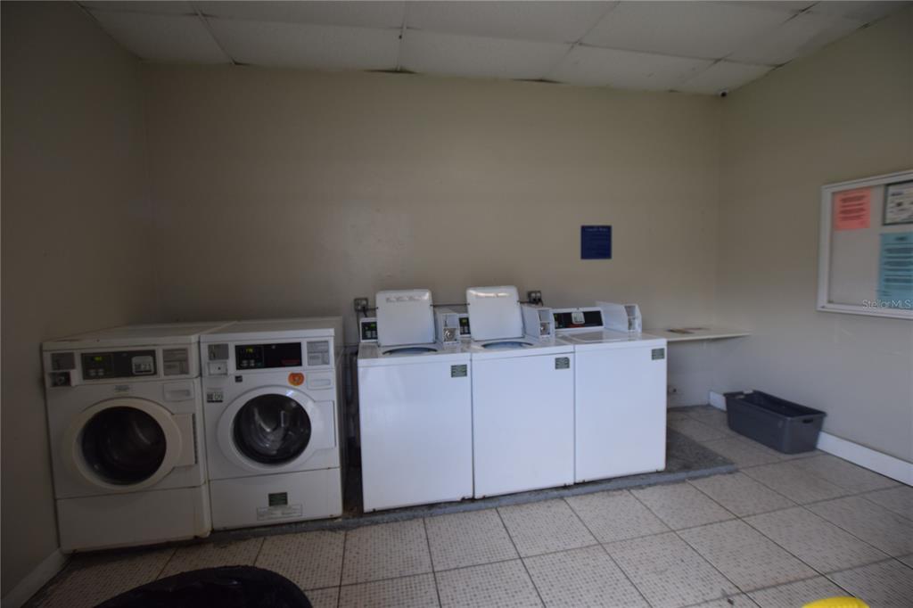 A laundry room featuring two front-load dryers and three top-load washing machines on tiled flooring — 1713 DIXON BOULEVARD UNIT 159, COCOA, FL