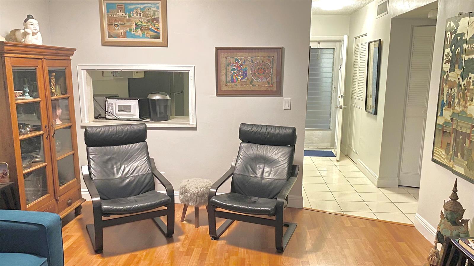 A living room features two black leather chairs, a wooden cabinet, and a kitchen pass-through window — 2724 Garden S # 207, Lake Worth FL 33461, LAKE WORTH, FL