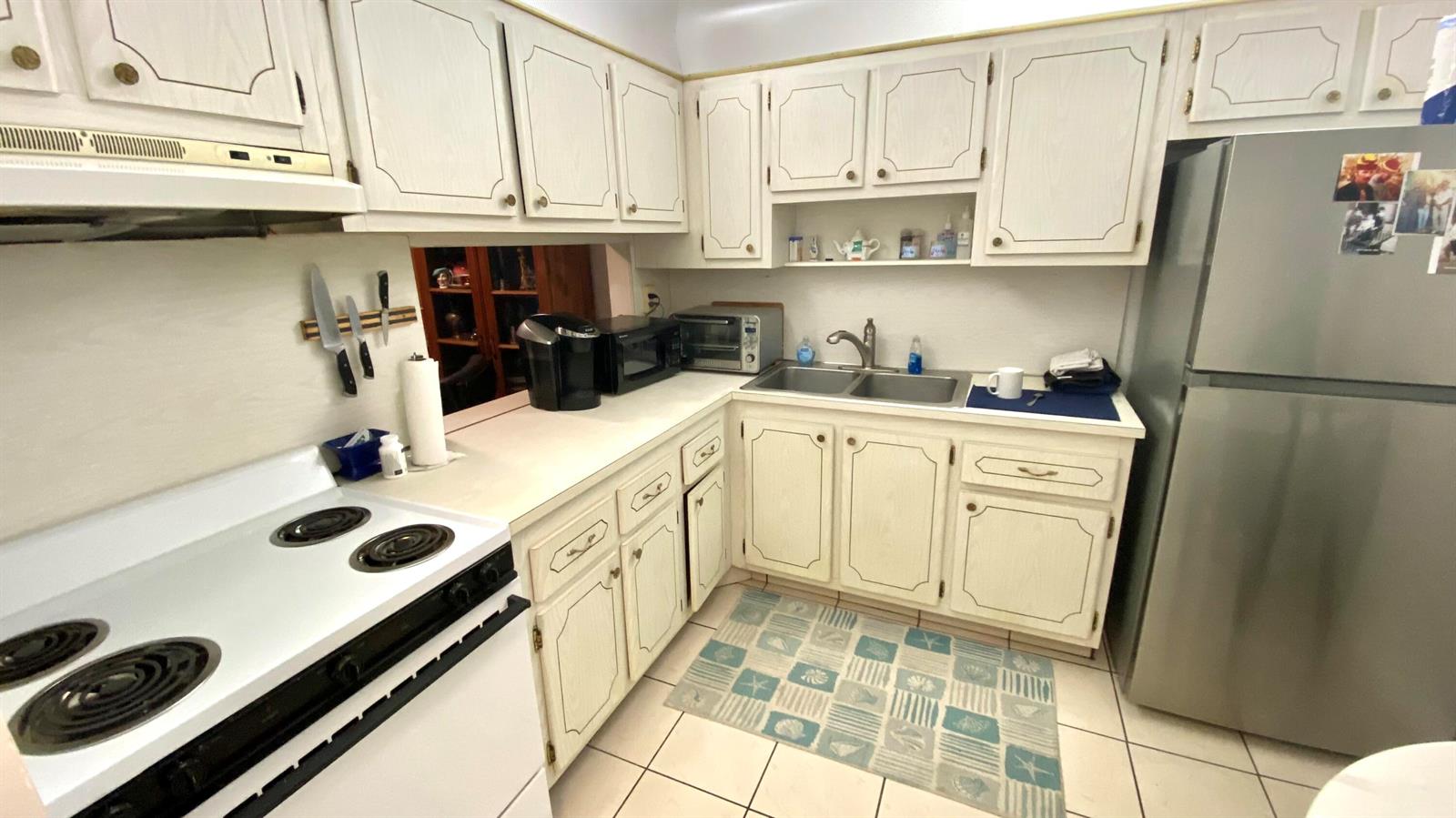 A kitchen features white cabinets, a stainless steel refrigerator, and a white electric stove — 2724 Garden S # 207, Lake Worth FL 33461, LAKE WORTH, FL