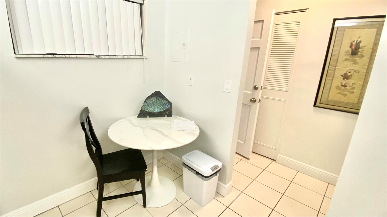 A small dining area features a white marble pedestal table, a black chair, and tile flooring — 2724 Garden S # 207, Lake Worth FL 33461, LAKE WORTH, FL