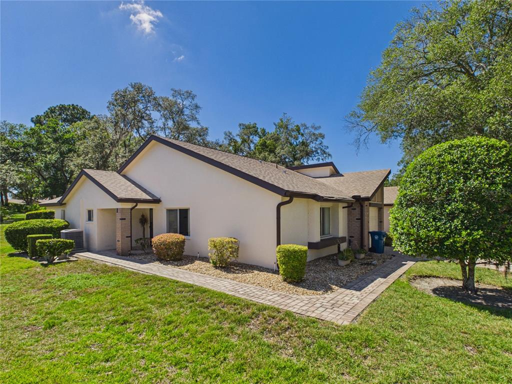 A single-story house with a beige exterior, brown trim, and a paved walkway in front — 7511 HEATHER WALK DRIVE, WEEKI WACHEE, FL