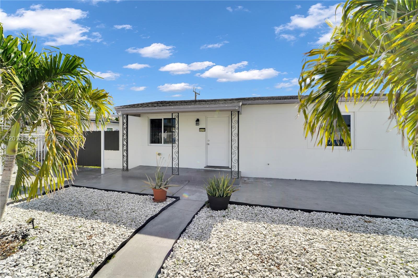 A single-story white house features a concrete front porch, gravel landscaping, and two palm trees — 9425 NW 36th Ave, Miami FL 33147, MIAMI, FL
